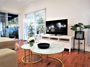 sala de estar con TV y mesa en Sydney Meets Miranda, Comfy 4 Bedrooms Corner House, en Miranda