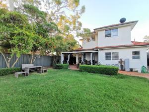 a white house with a yard with benches at Sydney Meets Miranda, Comfy 4 Bedrooms Corner House in Miranda