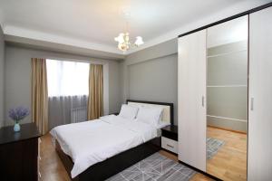 um quarto com uma cama branca e uma porta de vidro deslizante em Spacious central apartment em Almaty