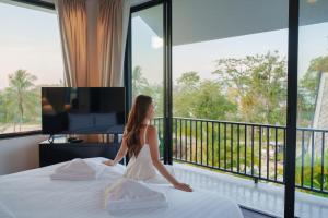 a woman sitting on a bed in front of a window at Yao Bada Badoo Boutique Resort in Ko Yao Yai