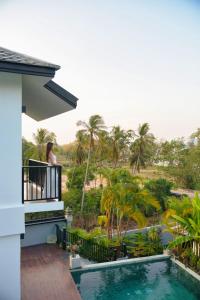 a woman standing on the balcony of a house with a swimming pool at Yao Bada Badoo Boutique Resort in Ko Yao Yai