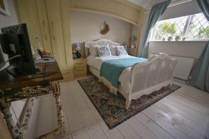 a bedroom with a bed and a desk and a television at Halwell Lodge in St Ives