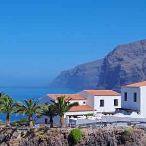 ein weißes Gebäude mit Palmen vor einem Berg in der Unterkunft Luxury Tagara Beach in Puerto de Santiago