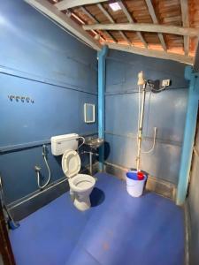 a blue bathroom with a toilet and a bucket at Castello's Coco Huts in Benaulim