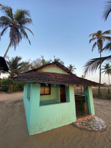 ein kleines Haus am Strand mit Palmen in der Unterkunft Castello's Coco Huts in Benaulim