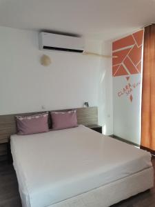 um quarto com uma grande cama branca com almofadas roxas em Clara Sea View em Burgas