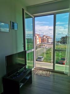 a living room with a flat screen tv and a large window at Clara Sea View in Burgas City