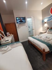 a bedroom with two beds and a flat screen tv at Richmond House in Great Yarmouth