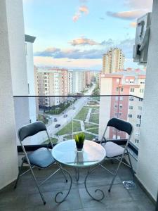 a table and chairs on a balcony with a view of a city at Bright Scandi Apartment in Skopje