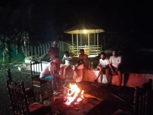 a group of people sitting around a fire at night at Cassa Cottage Munnar in Kallar Vattiyar