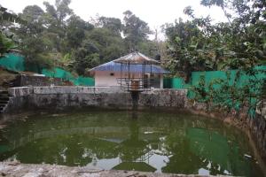 a pond in a garden with a small building at Cassa Cottage Munnar in Kallar Vattiyar