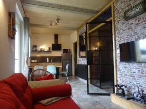 a living room with a red couch and a kitchen at La ferme aux chats in Formigny