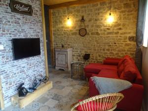 a living room with a red couch and a brick wall at La ferme aux chats in Formigny