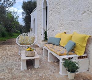 un sofá con almohadas amarillas y azules y una silla en Casa Baronessa, en Ceglie Messapica