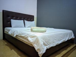 a bed with a black headboard and white sheets and pillows at Pondok Wisata DEPORIZ 2 in Porisgaga