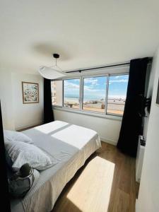 een slaapkamer met een bed en een groot raam bij Appartement T4 avec vue mer pour 7 personnes in Valras-Plage