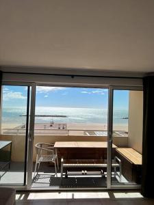 een kamer met een tafel en banken en uitzicht op de oceaan bij Appartement T4 avec vue mer pour 7 personnes in Valras-Plage
