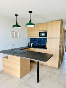 een keuken met een zwart aanrecht en houten kasten bij Appartement T4 avec vue mer pour 7 personnes in Valras-Plage