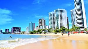 une plage avec de grands bâtiments et des gens dans l'eau dans l'établissement Seaflats Iate Plaza Hotel, à Fortaleza