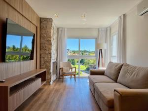 a living room with a couch and a television at Apartamentos Rossa Residenzialle CENTRO by Achei Gramado in Canela