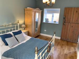 a bedroom with a bed with a blue comforter at The Little Coach House in Wales in Newtown