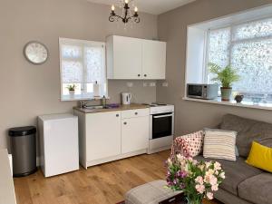 a kitchen with white cabinets and a couch in a living room at The Little Coach House in Wales in Newtown