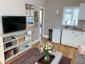 a living room with a television and a vase of flowers at The Little Coach House in Wales in Newtown