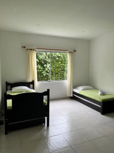 two beds in a room with a window at Casa Campestre Sol Naciente in La Tebaida