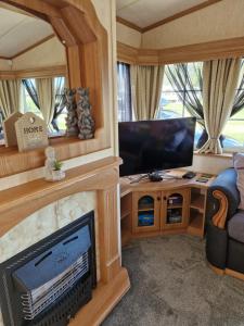 uma sala de estar com uma televisão de ecrã plano e um sofá em Static Caravan KL13 em Bettws-Evan