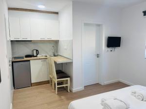 a small kitchen with white cabinets and a chair in a room at Viva Apartments in Përmet