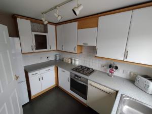 a kitchen with white cabinets and a stove top oven at Edelweiss House in Great Barr