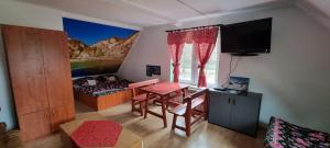 a room with a table and a bed and a television at Apartament Nad Dunajcem in Sromowce Niżne