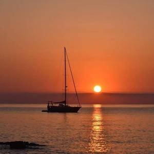a boat sitting in the water at sunset at Bed and Breakfast Le petunie in Bari Sardo