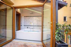 a bathroom with a tub and a glass wall at Falegnami Boutique Suites - BolognaRooms in Bologna