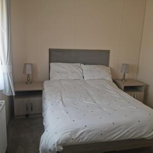 a bedroom with a white bed with two lamps at Homeston Lodge in Drumlemble