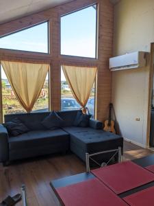 a living room with a blue couch and large windows at Cabaña Coigües Balneario Punta de Lapas in Quellón