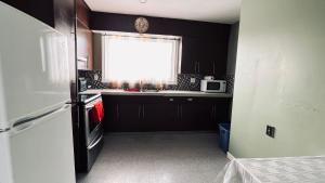 a kitchen with black cabinets and a window and a refrigerator at Private Rooms Male Accommodation Close to NAIT Kingsway Mall Downtown in Edmonton