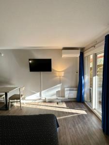 sala de estar con TV de pantalla plana en la pared en Joli studio Arles avec terrasse et verdure, en Arles