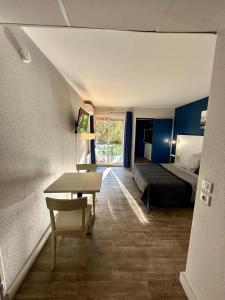 Habitación de hotel con cama, escritorio y mesa. en Joli studio Arles avec terrasse et verdure, en Arles