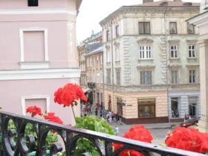 a view of a city from a balcony with red flowers at Old Town Apartments in Lviv