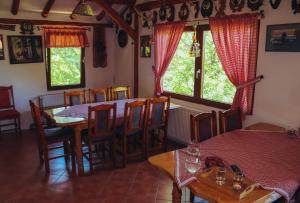 uma sala de jantar com mesa, cadeiras e janelas em Etno domaćinstvo Milenković em Despotovac
