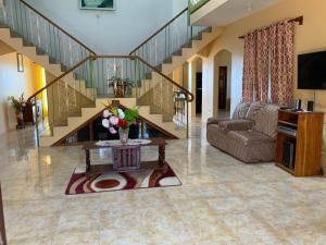 ein Wohnzimmer mit einer Treppe und einem Tisch mit Blumen in der Unterkunft Poinciana House in Montego Bay