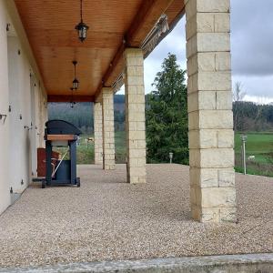 un patio al aire libre con techo de madera y parrilla en LE VIEUX SAULE en Curgy
