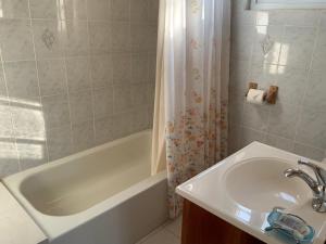 a bathroom with a sink and a tub and a shower at Poinciana House in Montego Bay