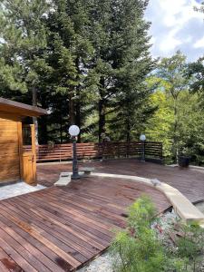 a wooden deck with benches and a fence and trees at Chalet Leonard House in the wood in Pennabilli