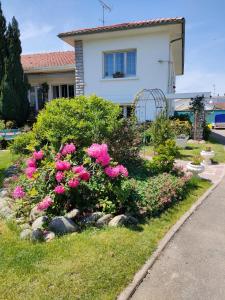 una casa con flores rosas delante de un patio en Chambre d'hôtes Les Hortensias en Gelos