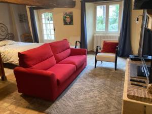 a living room with a red couch and a bed at chambre privée in Lombron
