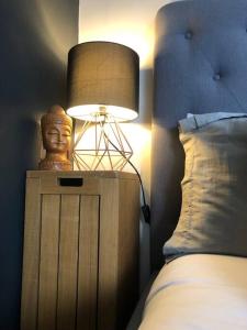 een lamp op een nachtkastje naast een bed bij Beautiful Totnes home with parking in Totnes