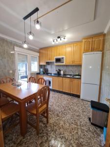 Valle Paraiso في Cepeda: مطبخ مع طاولة خشبية وثلاجة بيضاء