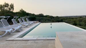a row of white chairs sitting around a swimming pool at Lacinera Trulli e Lamie in Ostuni